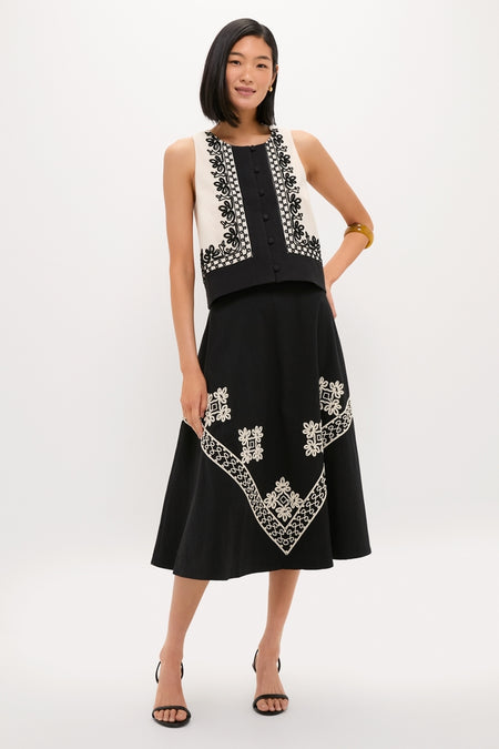 Woman in a classic, coordinated two-piece featuring the high-end Soutache Cotton Andrea Circle Skirt and a sleeveless knit vest, exuding effortless style with fun, embroidered patterns.
