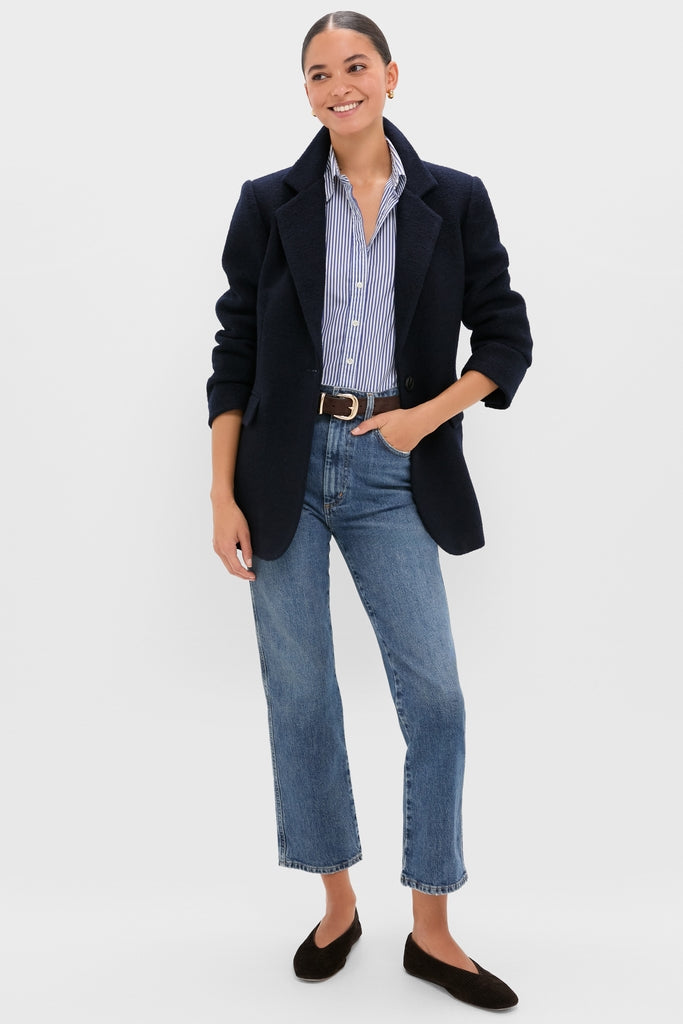 Young woman showcasing the Navy Boucle Leo Blazer with a classic, tailored look. Effortlessly styled over a striped shirt and jeans, embodying high-end, fun sophistication.