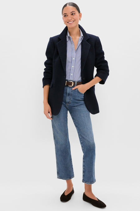 Young woman showcasing the Navy Boucle Leo Blazer with a classic, tailored look. Effortlessly styled over a striped shirt and jeans, embodying high-end, fun sophistication.