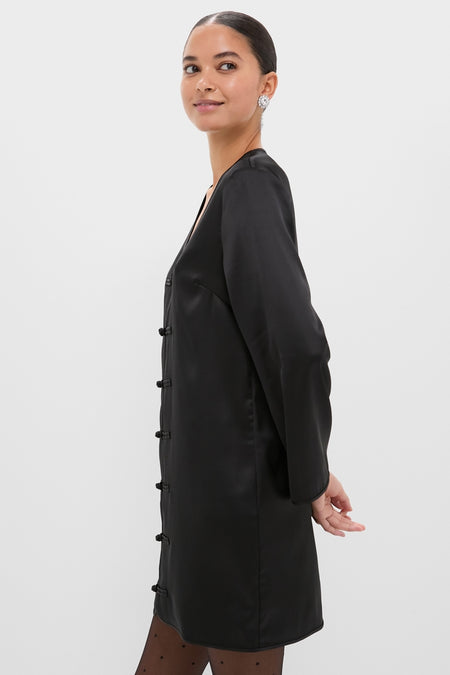 Woman in profile wearing the classic Black Satin Tatiana Dress with elegant frog closures, paired with dotted tights; an effortless, high-end look for fun, elevated occasions.