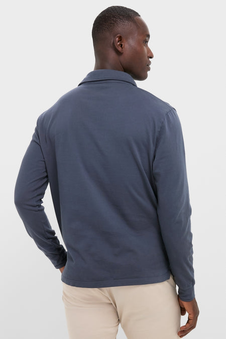 Back view of a man wearing the classic Faded Navy Garment Dyed Long Sleeve Polo, showcasing its effortless style and comfort, paired with light-beige trousers.