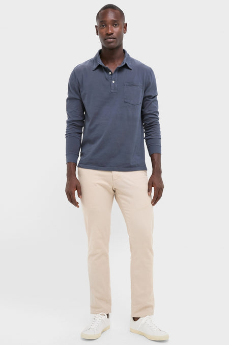 Man models the Faded Navy Garment Dyed Long Sleeve Polo, showcasing its classic, effortless style with a relaxed pose, epitomizing high-end, fun fashion.