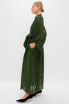 A woman models the classic Forest Green Lace Calliope Dress with puffed sleeves, satin sash, and pockets, embodying an effortless, high-end style.