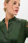 Woman wearing the Forest Green Lace Calliope Dress, featuring a classic mandarin collar and intricate sleeve detailing, paired with elegant green stone earrings for an effortless, high-end look.