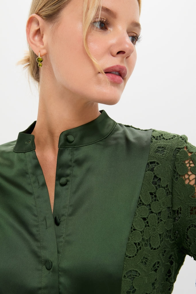 Woman wearing the Forest Green Lace Calliope Dress, featuring a classic mandarin collar and intricate sleeve detailing, paired with elegant green stone earrings for an effortless, high-end look.