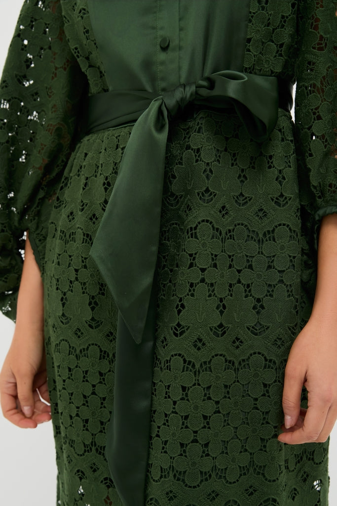 Forest Green Lace Calliope Dress features classic floral lace, an effortless satin bow at the waist, and a fun, high-end design perfect for any occasion.