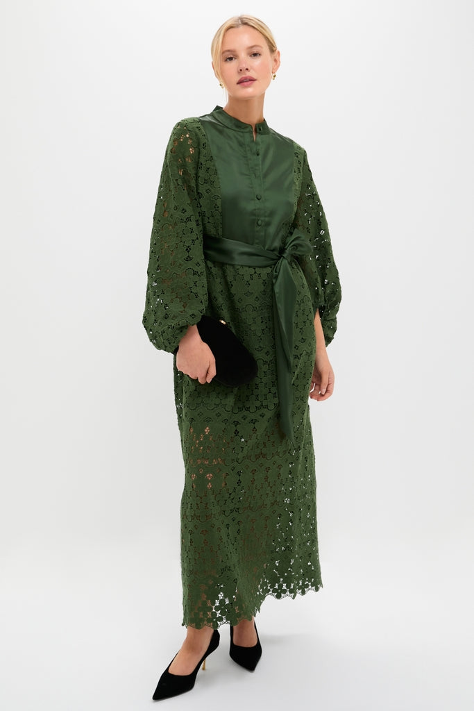 Model wearing the Forest Green Lace Calliope Dress, featuring a classic mandarin collar, elegant lace details, and an effortless satin sash, paired with a small clutch and heels.