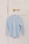 Blue Stripe Mateo Long Sleeve Shirt with mandarin collar and chest pocket, hanging on a door. Classic and effortless high-end style for fun and smart-casual occasions.