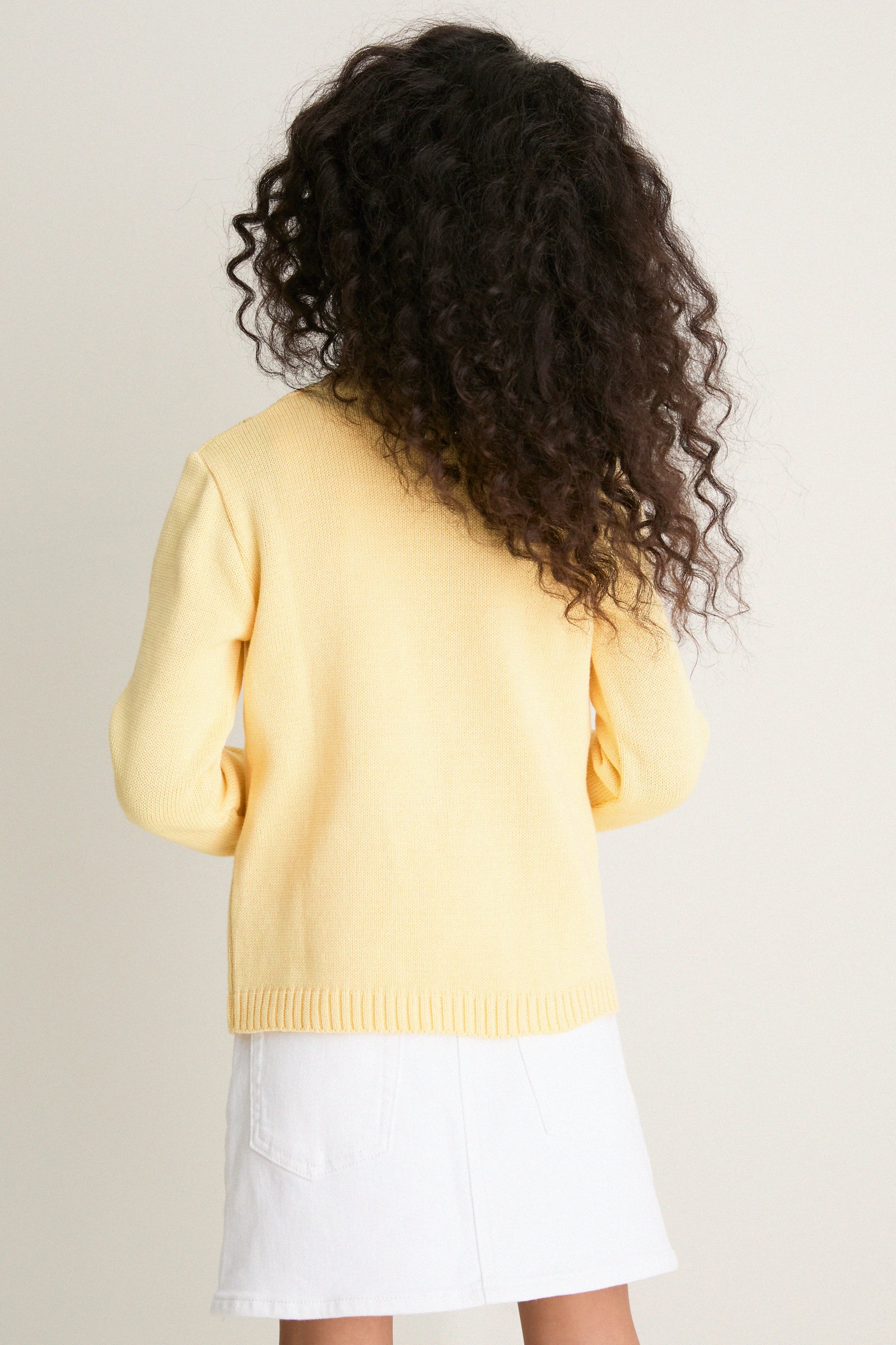 Person wearing the classic Lemon Espina Cotton Cardigan, featuring an effortless zig-zag pointelle pattern and fun floral embroidery, embodying high-end, timeless style.
