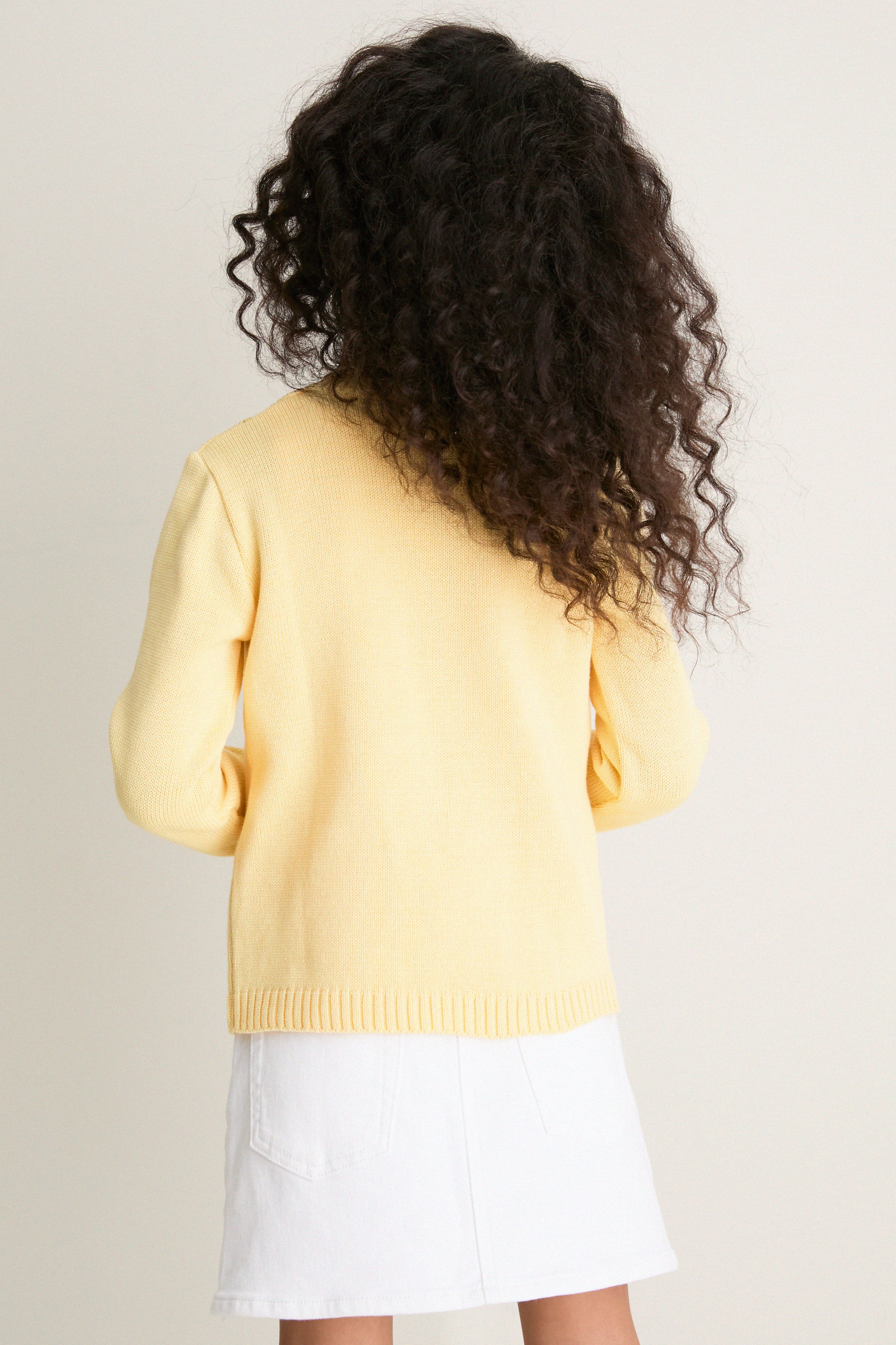 Person wearing the classic Lemon Espina Cotton Cardigan, featuring an effortless zig-zag pointelle pattern and fun floral embroidery, embodying high-end, timeless style.