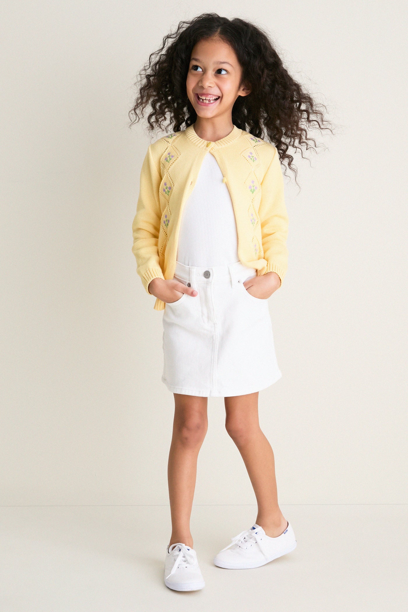 Young girl in a classic Lemon Espina Cotton Cardigan, showcasing fun and effortless high-end design with floral embroidery and pointelle details, embodying Tuckernuck's cool, confident style.