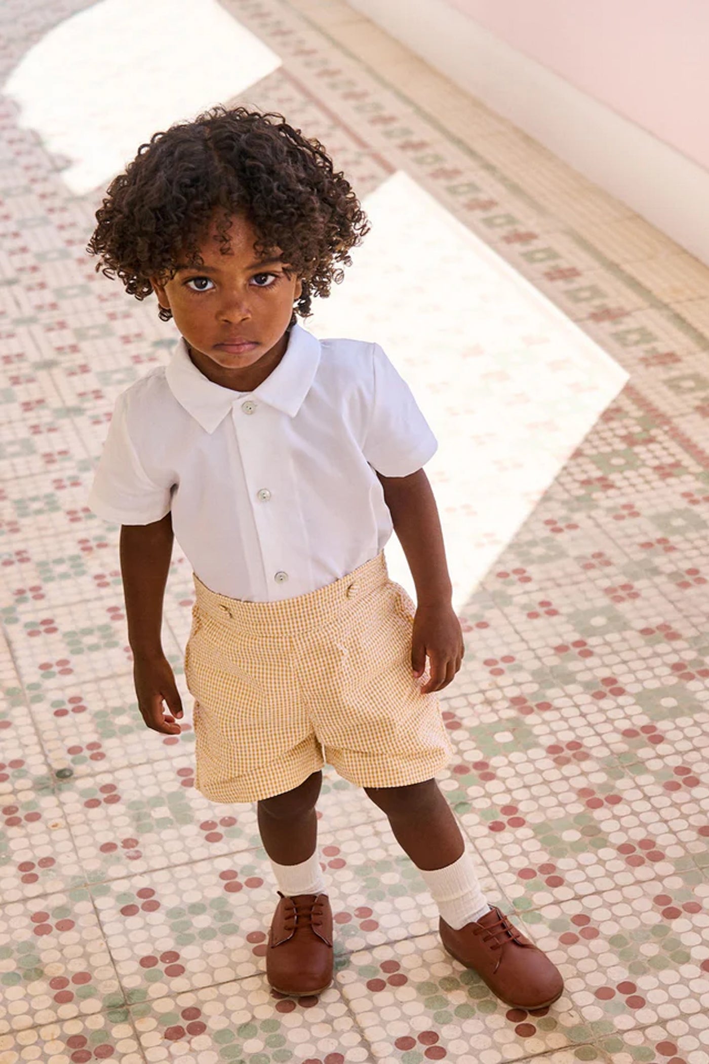 Young child in the classic Yellow Gingham Oliver Baby Boy Set, featuring an effortless, high-end white shirt and fun gingham shorts, embodying playful sophistication.