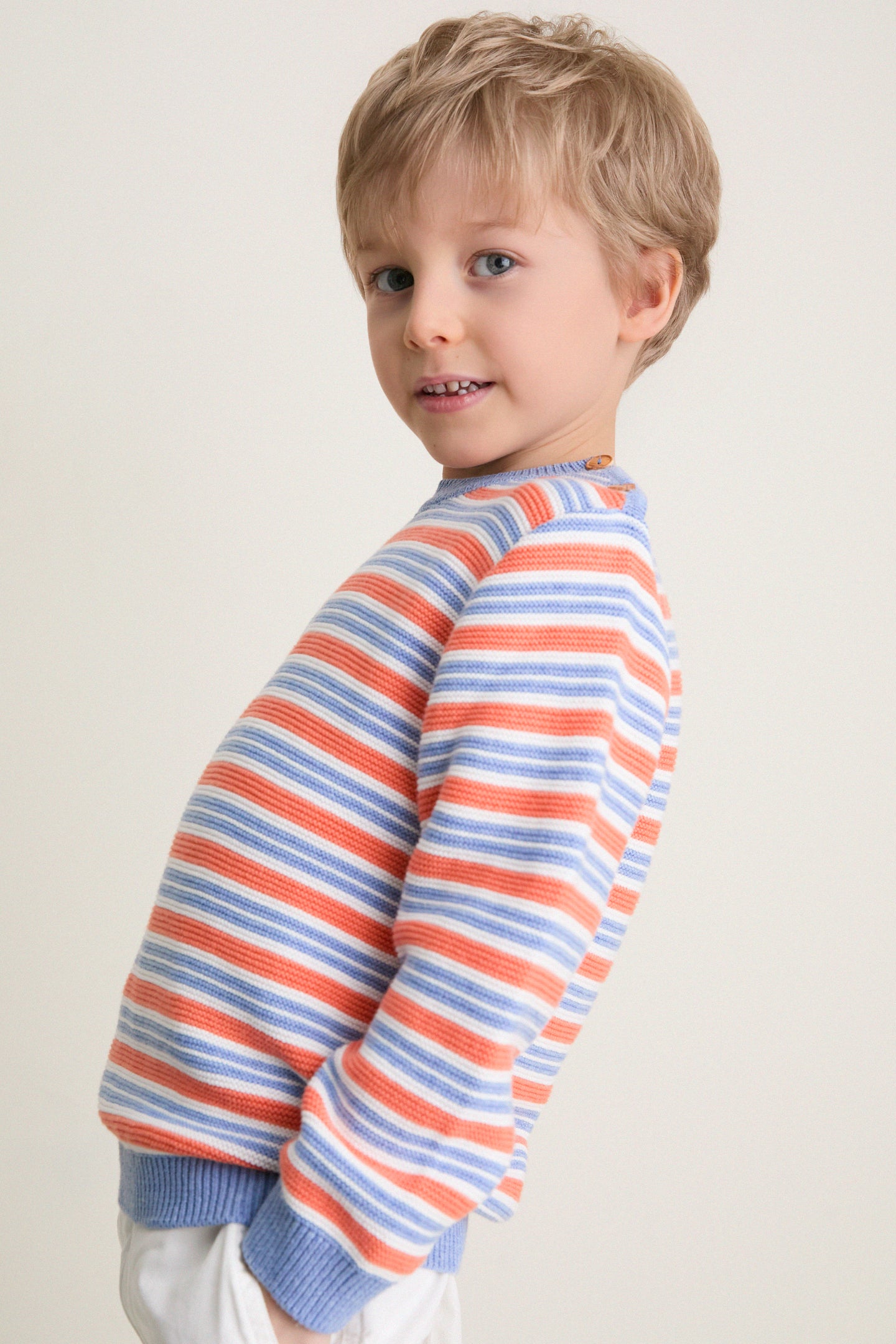 Child wearing Coral Stripe Bromo Cotton Jumper with classic ribbed trims and wooden buttons, embodying effortless, high-end style. Perfect for a fun, everyday look.