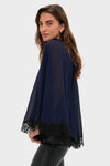 Woman in profile wearing the classic Navy Cape Chiffon Ashfield Top, showcasing an effortless, high-end look with its mock neck, cape silhouette, and bow detail.