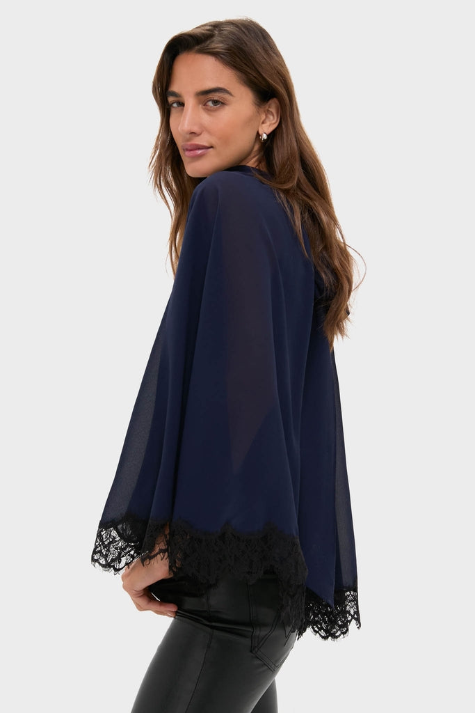 Woman in profile wearing the classic Navy Cape Chiffon Ashfield Top, showcasing an effortless, high-end look with its mock neck, cape silhouette, and bow detail.