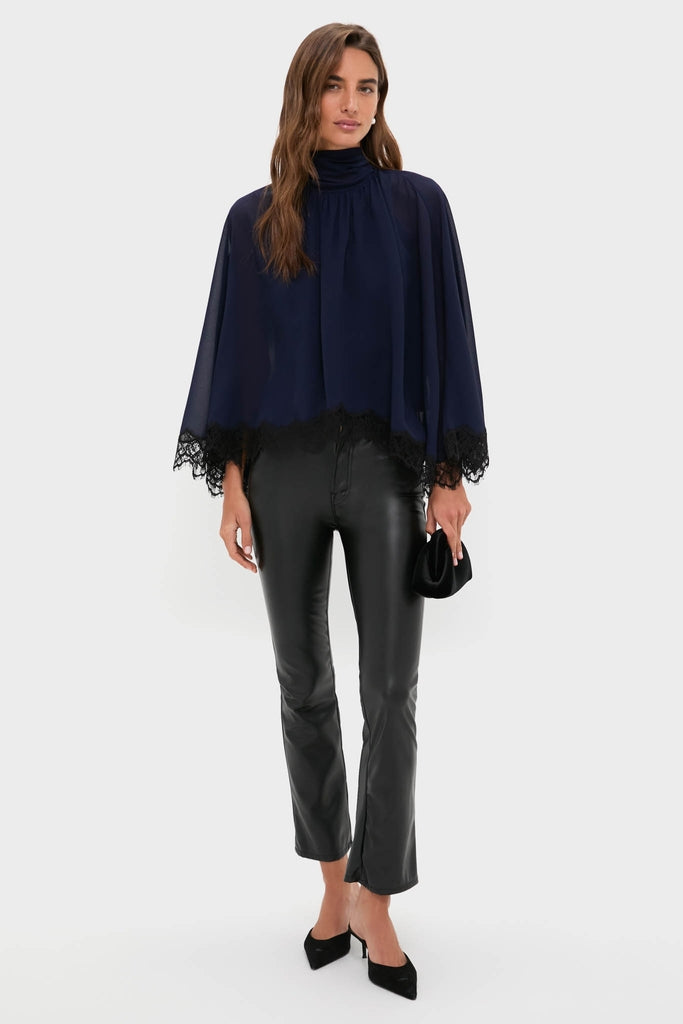 Model wearing the classic Navy Cape Chiffon Ashfield Top with a high neck and bow detail, paired with black leather pants and heels, exuding effortless and high-end style.