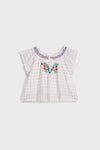 Cream Cruise Checks Perlane Blouse: Classic, airy cotton top with flutter sleeves, scalloped edges, and vibrant floral embroidery. An effortless, fun, high-end piece for your little one's wardrobe.