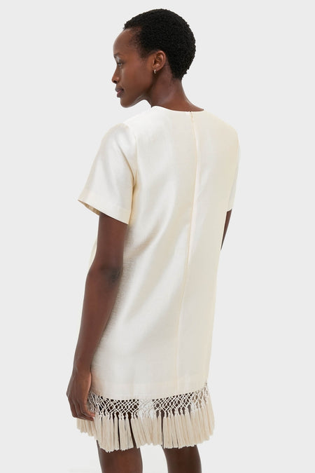 Woman models the Winter White Tassel Dupioni Downing Dress, showcasing its classic shift silhouette, fun fringe hem, and high-end, effortless design that's perfect for festive occasions.