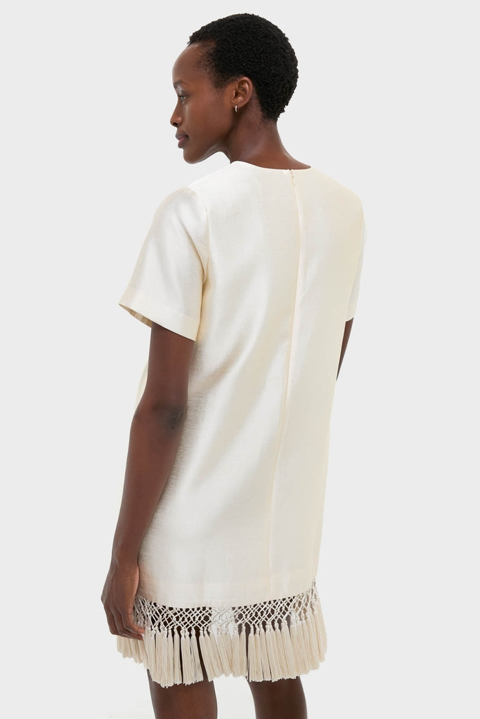 Woman models the Winter White Tassel Dupioni Downing Dress, showcasing its classic shift silhouette, fun fringe hem, and high-end, effortless design that's perfect for festive occasions.