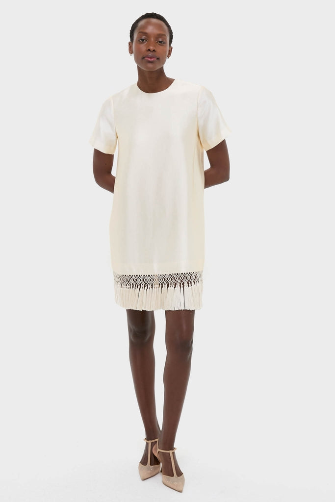 Winter White Tassel Dupioni Downing Dress: A classic, high-end shift dress with an effortless macramé fringe hem, perfect for fun holiday gatherings, paired with elegant T-strap heels.