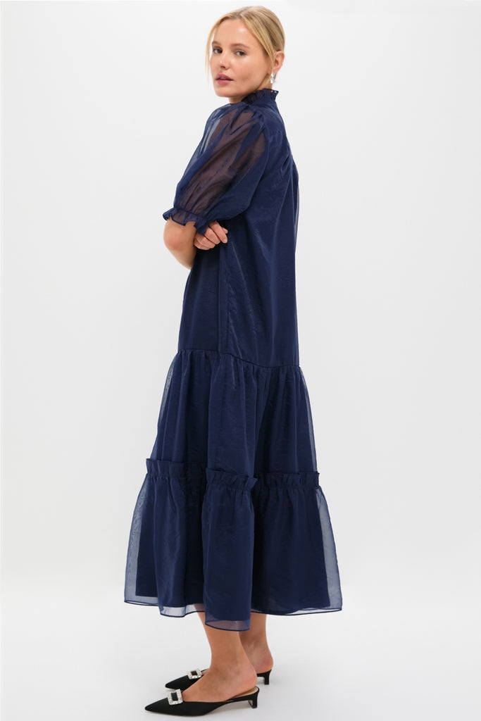 Navy Chiffon Selena Maxi Dress features a classic tiered silhouette with sheer puff sleeves and a ruffled high neckline, exuding effortless, high-end, and fun elegance.