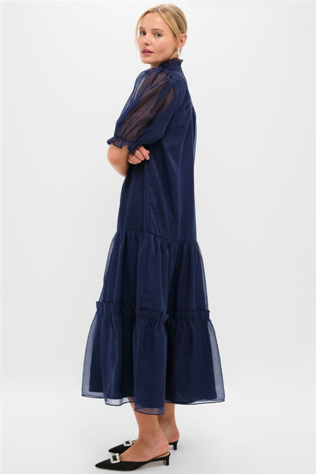 Navy Chiffon Selena Maxi Dress features a classic tiered silhouette with sheer puff sleeves and a ruffled high neckline, exuding effortless, high-end, and fun elegance.