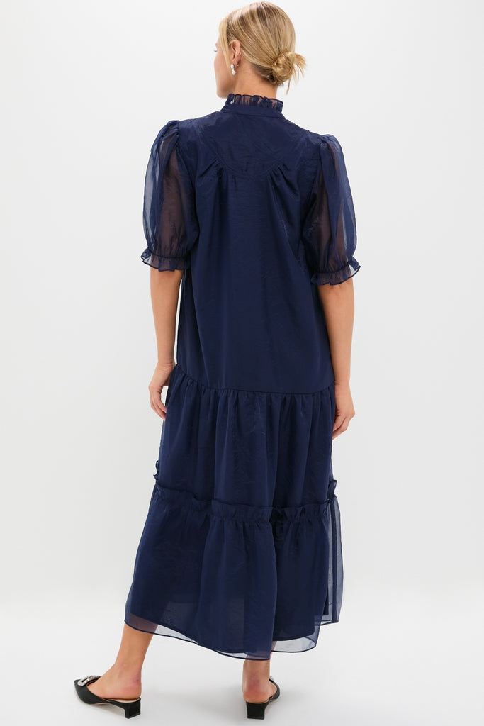 Navy Chiffon Selena Maxi Dress featuring a ruffled collar, puff sleeves, and tiered skirt. Classic, effortless, and fun, perfect for high-end holiday festivities.