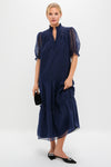 Woman models the Navy Chiffon Selena Maxi Dress, featuring a classic ruffled collar, sheer puff sleeves, and a tiered skirt. Effortless and high-end, perfect for fun occasions.