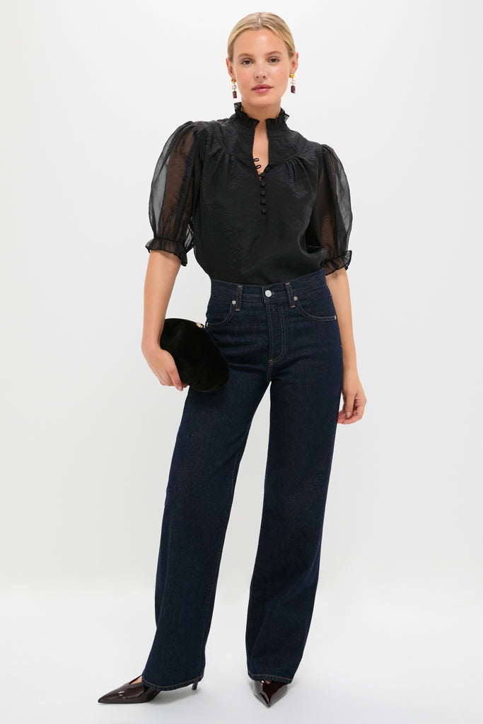 Model wearing the Black Chiffon Selena Blouse with ruffled collar and sheer puff sleeves, paired with chic high-waisted jeans and heels, exuding classic, effortless elegance.