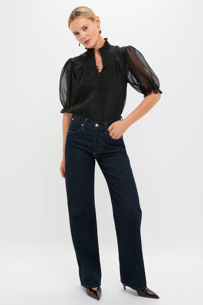 Classic Black Chiffon Selena Blouse with ruffle collar, puff sleeves, and covered buttons, styled effortlessly with jeans and heels for a fun, high-end look.