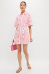 Young woman in the Red Stripe Maddie Mini Dress, a classic, effortless shirt-dress with a rope belt, accessorized with sandals and a pink handbag for a fun, high-end look.