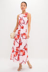 Woman in Lani Maxi Dress with vibrant floral print and knotted waist detail, holding a beige clutch, embodying classic, effortless style with a fun, high-end appeal.