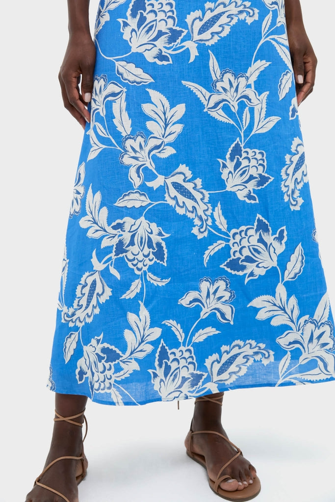 Wearing the Ren Cut Out Maxi Dress, showcasing its classic bright blue floral-and-foliage print, paired with effortless tan leather strappy flat sandals for a high-end, fun look.