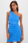 Woman in Blue Saskia Mini Dress, featuring a one-shoulder design, gathered waist, and elegant tie, exuding an effortless, high-end style perfect for any occasion.