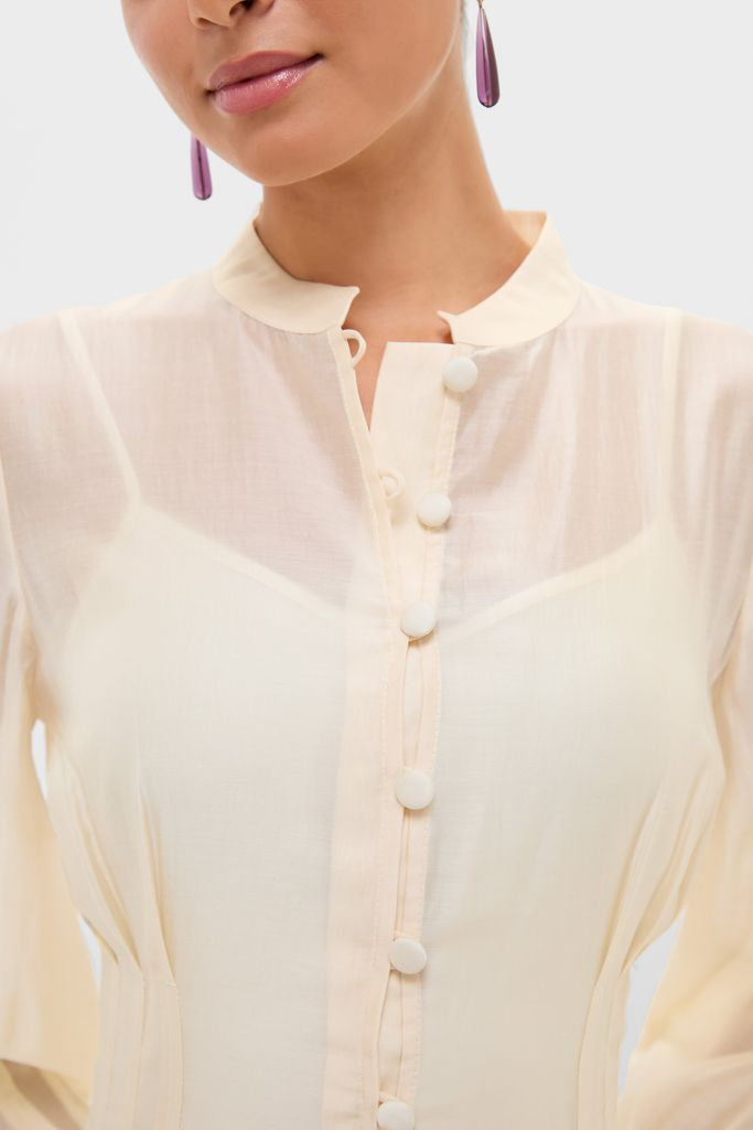 Classic and effortless, the Champagne Organza Marbella Dress features a mandarin collar, fabric-covered buttons, and elegant pintucks, perfect for high-end occasions, exuding fun sophistication.