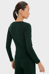 Woman in a classic, effortless deep-green ribbed set, with Forest Pointelle Slim Fit Long Sleeve Tee, embodying a fun, high-end style against a gray backdrop.