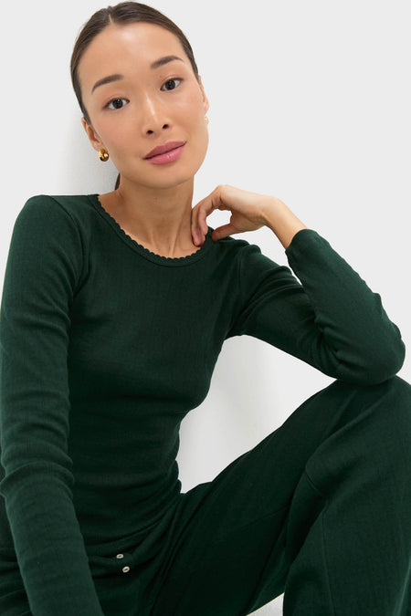 Person wearing Forest Pointelle Slim Fit Long Sleeve Tee with scalloped neckline and rib-knit fabric, embodying classic, effortless style. Paired with matching trousers and gold hoop earrings.