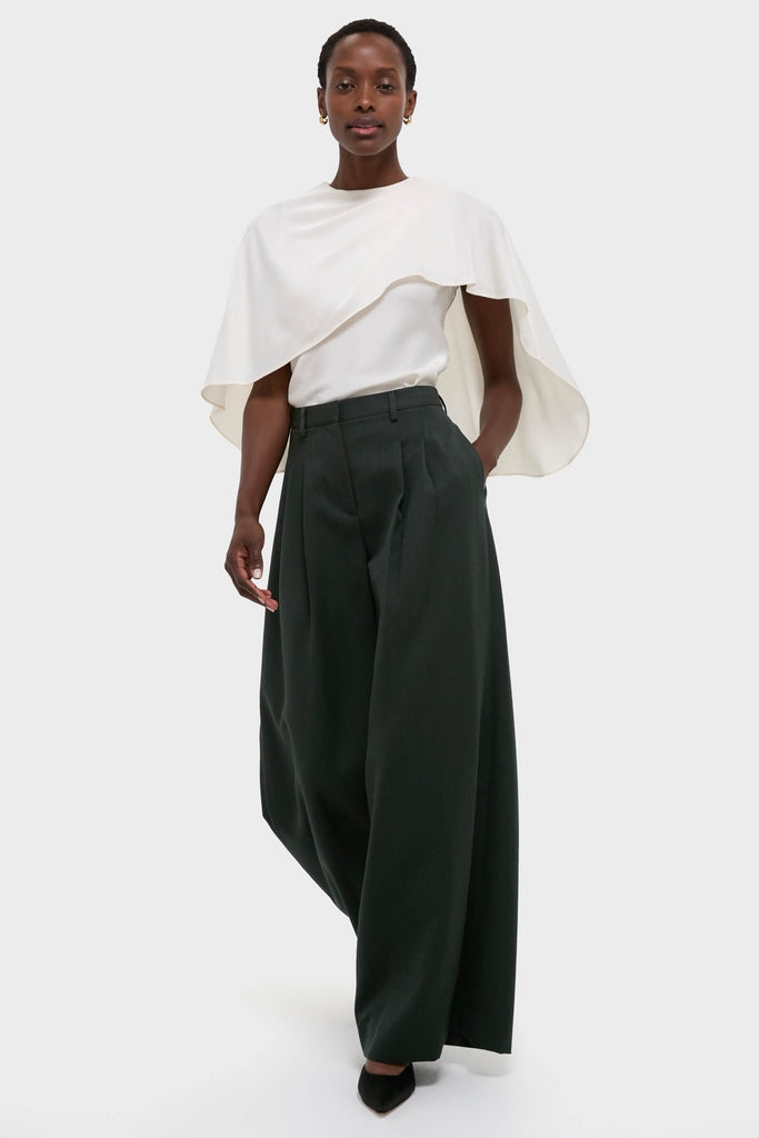 Model wearing the classic Cream Eliora Cape Top, featuring an asymmetric drape and relaxed fit, paired with high-end wide-leg trousers for an effortless, fun look.