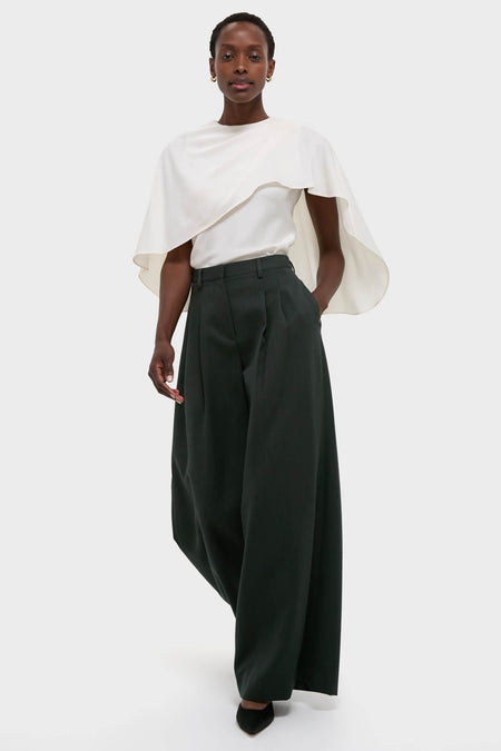 Model wearing the classic Cream Eliora Cape Top, featuring an asymmetric drape and relaxed fit, paired with high-end wide-leg trousers for an effortless, fun look.