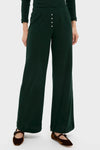 Person wearing classic Forest Pointelle Boxer Pants: dark-green, wide-leg, rib-knit design with elastic waistband, button placket, and brown Mary Jane flats for an effortless, high-end look.