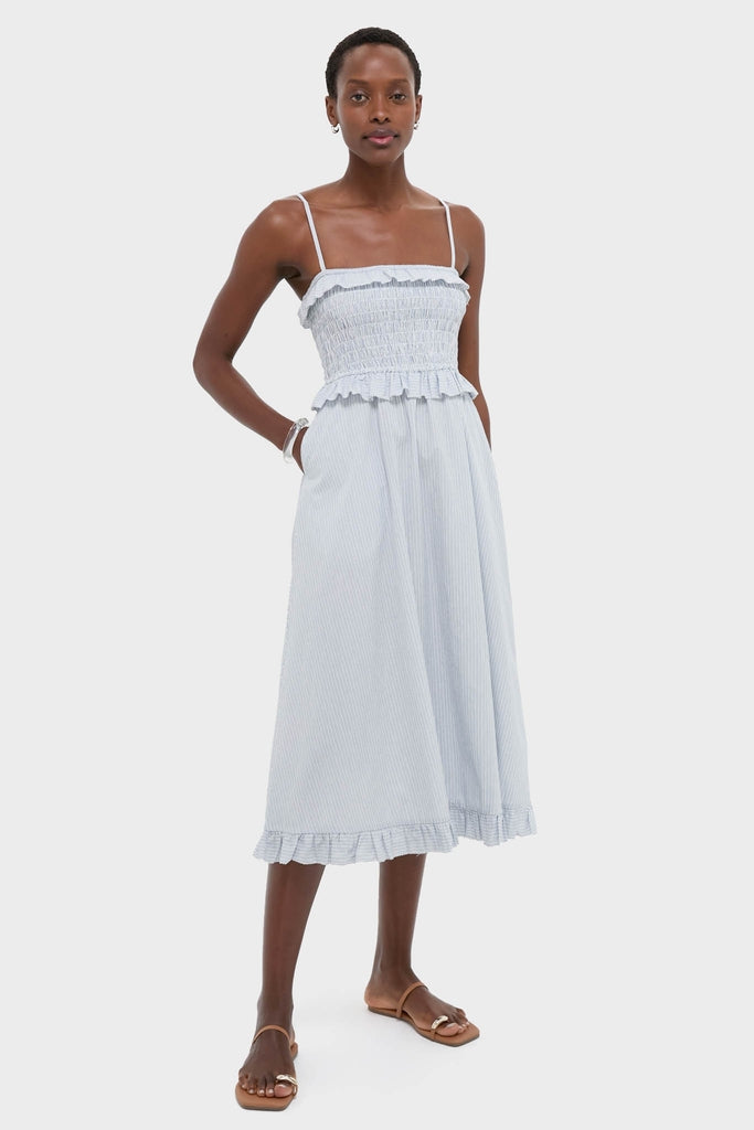 Effortlessly chic, the Blue and White Stripe Karine Midi Dress features a classic smocked bodice, adjustable straps, ruffle trim, and side pockets, embodying high-end, fun style.