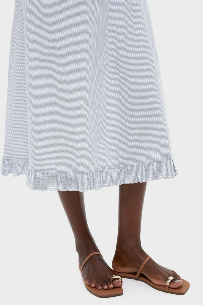 Person wearing the Blue and White Stripe Karine Midi Dress with ruffle hem and tan flat sandals, embodying an effortless and classic high-end style for fun, endless weekends.