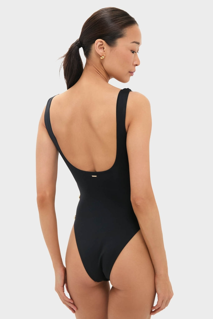 Woman wearing classic Black Mona Scoop Neck One Piece with low scoop back, silver-tone side hardware, and small gold hoops; effortless, high-end beachwear for a fun, confident style.