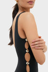Woman in Black Mona Scoop Neck One Piece with oval side cut-outs and shiny rings; an effortless, high-end swimsuit blending classic style with fun, cheeky details.