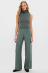 Woman models the Eucalyptus Zoe Sleeveless Turtleneck with high-waisted trousers, embodying an effortless, high-end style. The classic, minimalist ensemble is both fun and sophisticated.