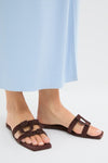 Cacao Simkhai Monogram Suede Flat Slides on feet, showcasing classic, effortless style with two broad decorative straps, embodying fun, high-end fashion from Tuckernuck.