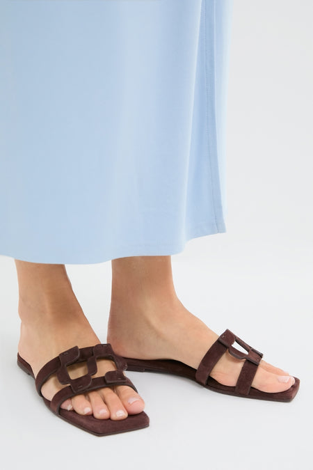 Cacao Simkhai Monogram Suede Flat Slides on feet, showcasing classic, effortless style with two broad decorative straps, embodying fun, high-end fashion from Tuckernuck.