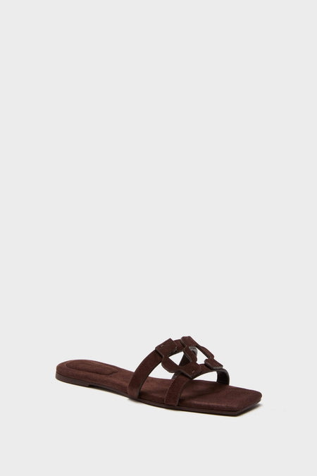 Cacao Simkhai Monogram Suede Flat Slides: Classic chocolate-brown suede flat mules with a square toe and two straps, featuring an interlocking ornament for an effortless, high-end look.