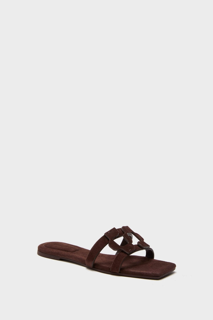 Cacao Simkhai Monogram Suede Flat Slides: Classic chocolate-brown suede flat mules with a square toe and two straps, featuring an interlocking ornament for an effortless, high-end look.