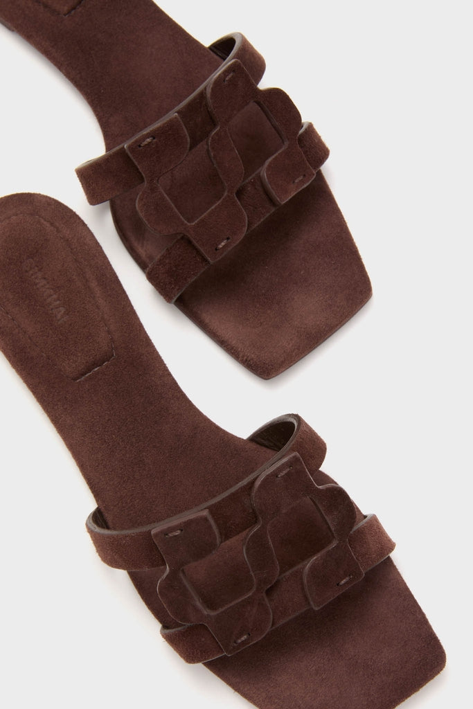 Cacao Simkhai Monogram Suede Flat Slides: classic brown suede mules with an open-toe, squared-off design and decorative strap, offering effortless fun and high-end style.